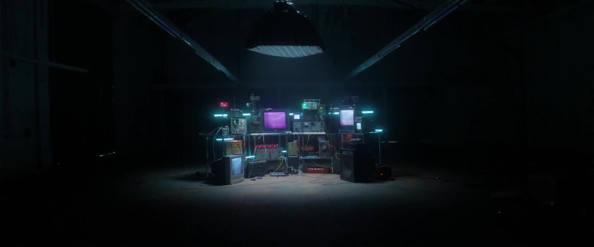 Vintage technology piled up under a spotlight inside a dark room