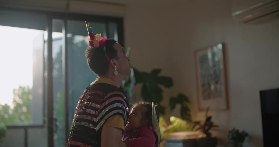 Father and toddler daughter wearing costumes playing on the living room at morning