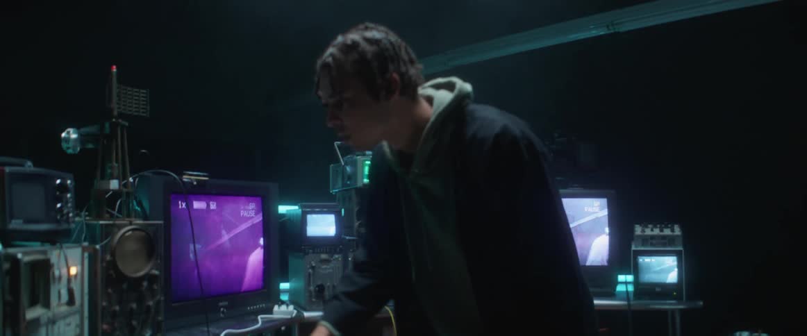 Young man looking around inspecting electronic equipment inside a dimly lit room