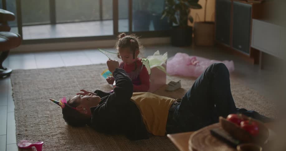 Father laying on carpet as daughter dresses up his face