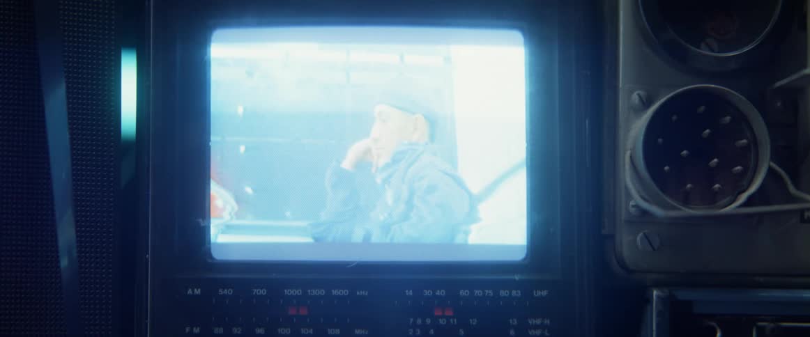 A display playing a video of a man sitting on a mass transit train traveling at night