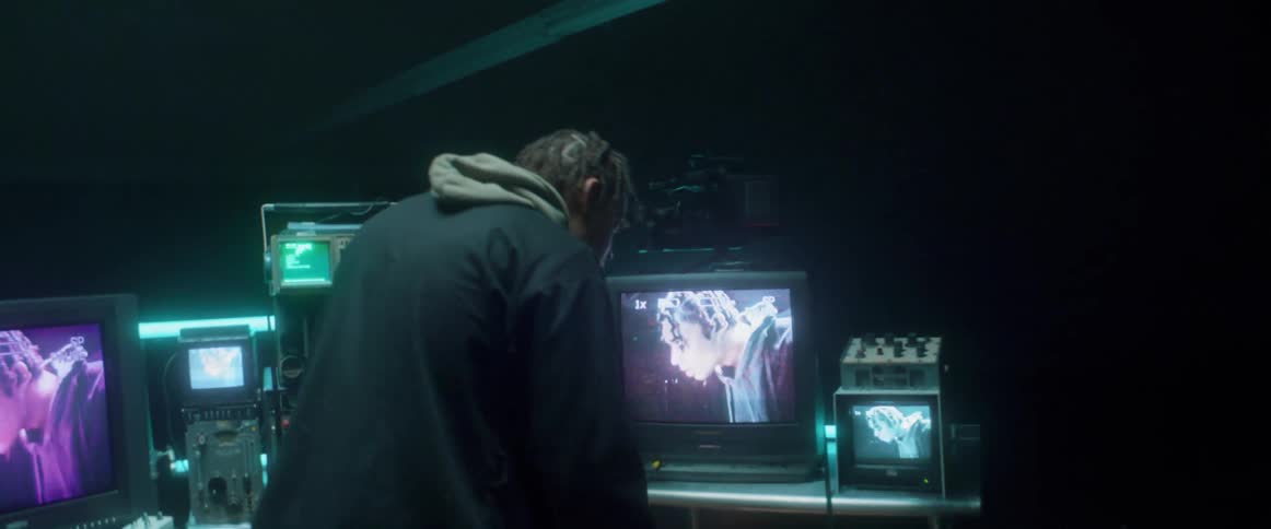 A man is in a room with televisions and monitors hooked up to cameras watching him and he is turning dials