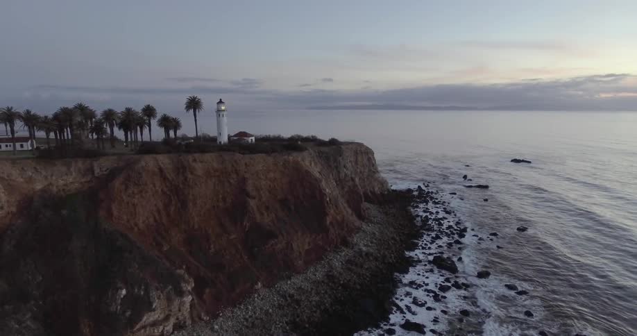 A coastline with a lighthouse at sunset