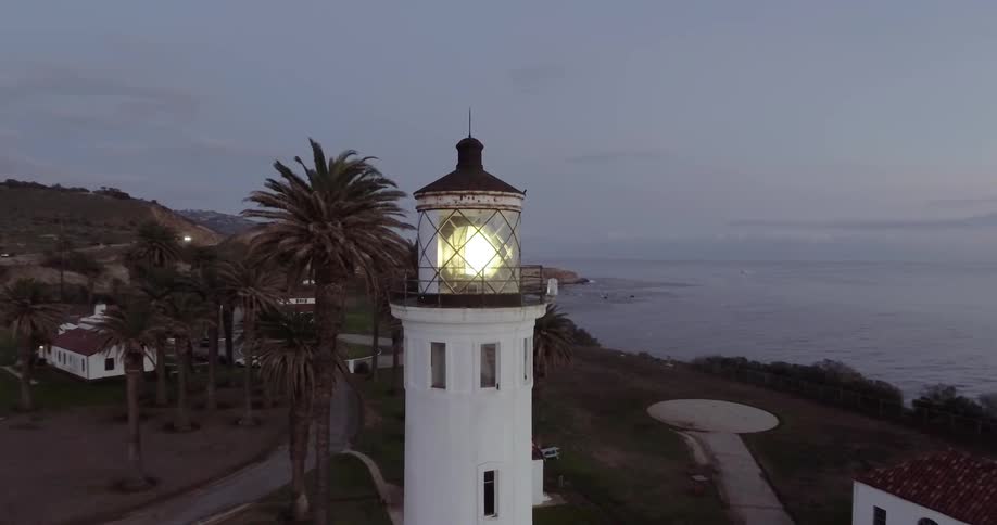 Moving around the top of a lighthouse as it shines light at sunset