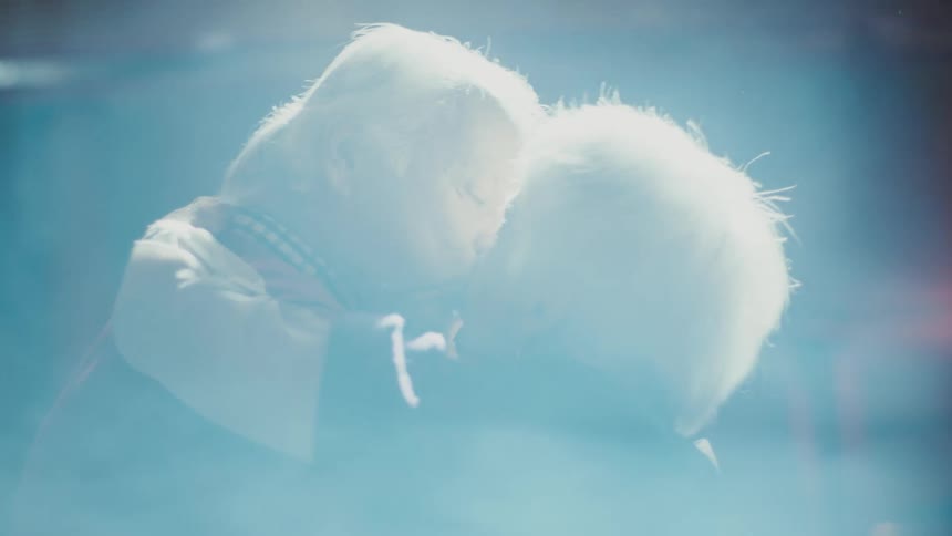 An elderly couple dances and kisses