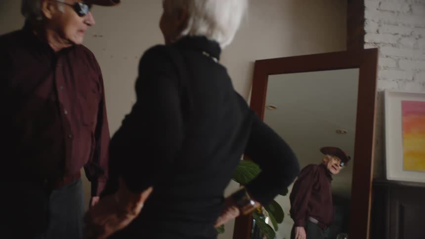 A woman puts a pirate hat on her husbands head then hands him a sword to go with his hook