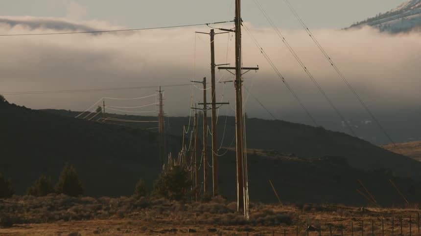 A shipping truck drives past electrical power cables in a field