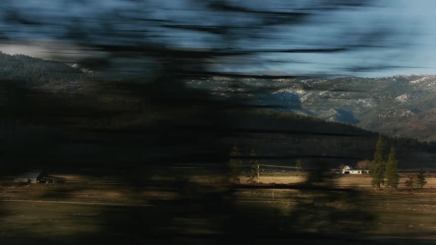 Traveling on a country road with a few houses far apart and forested mountains