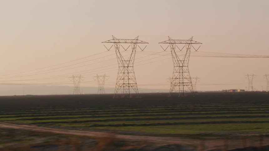 Large transmission towers in a rural countryside during the day