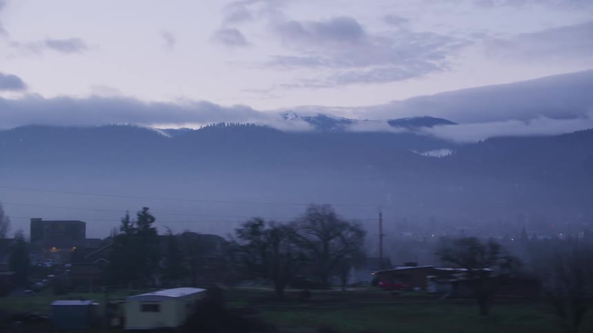 Traveling past a town with a mountain ridge behind it