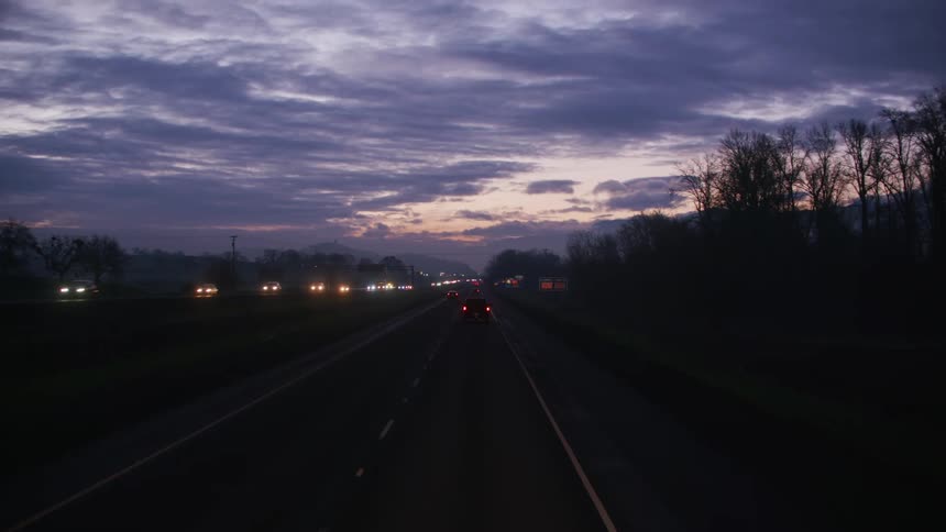 Vehicles driving on the highway through the countryside at evening