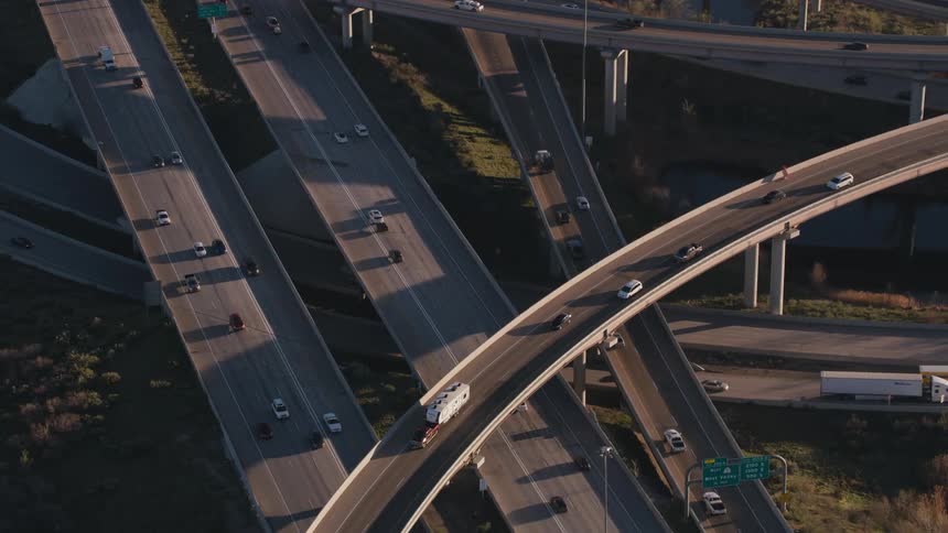 Traffic travels along an overpass in a highway interchange during the day