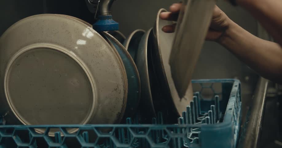 A person is loading dishes in the dishwasher
