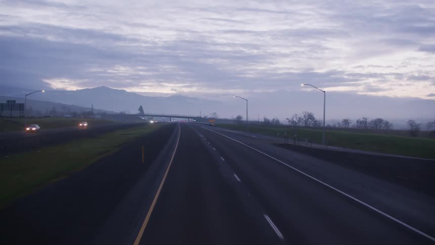 Traveling on a highway with the silhouette of mountains in the clouds