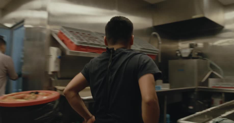 A restaurant employee ties on his apron and goes to wash dishes