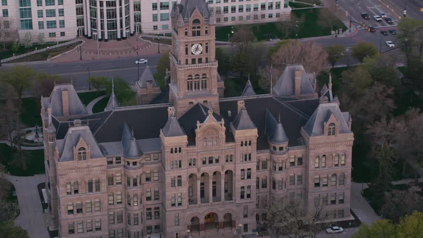Cars travel past the salt lake city and county building with clock tower