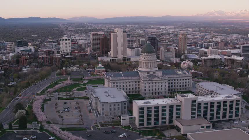 A capitol building with a dome on top and the surrounding city with mountains in the distance