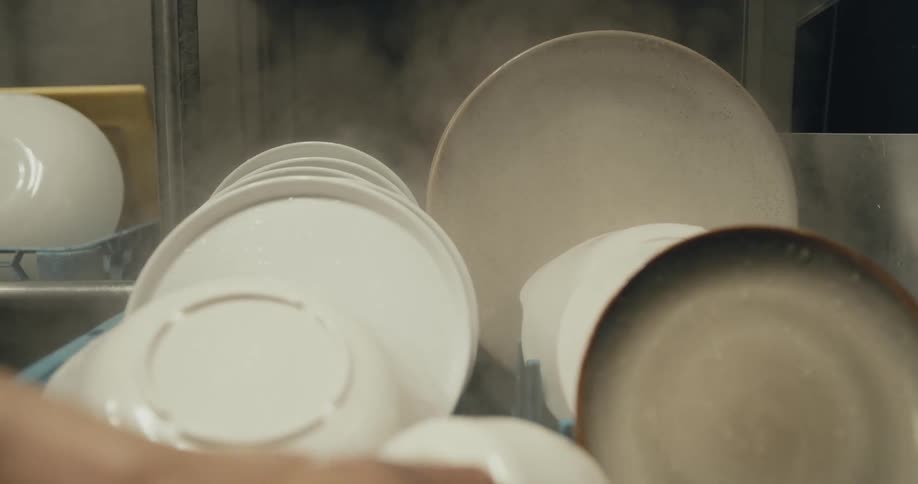 A person is washing dishes with a machine