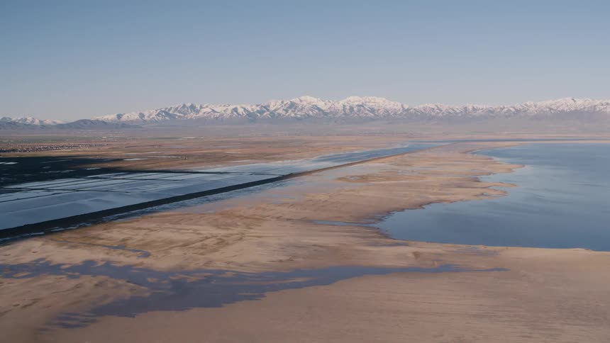 Aerial view of salt lakes on the desert flats close to the snow covered mountains