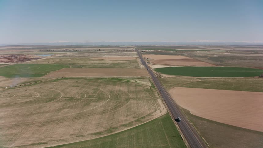 Trucks travel on a highway with farm land and fields on both sides