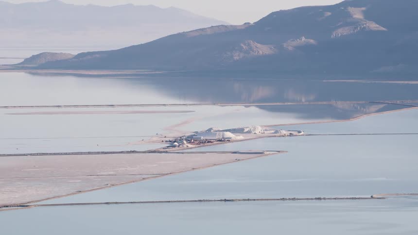 Mist covered mountains sit across reflective lakes from work site