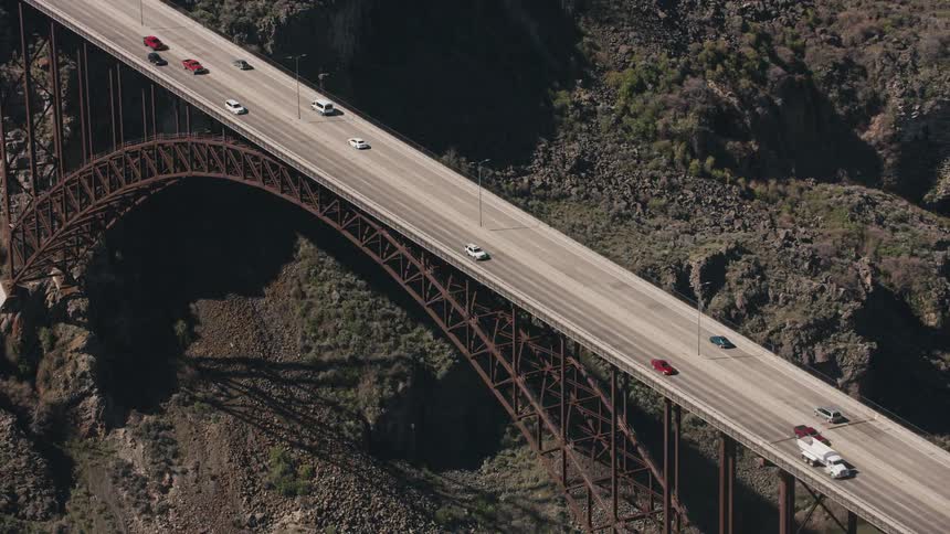 Aerial view of vehicles driving over an arched bridge over a river