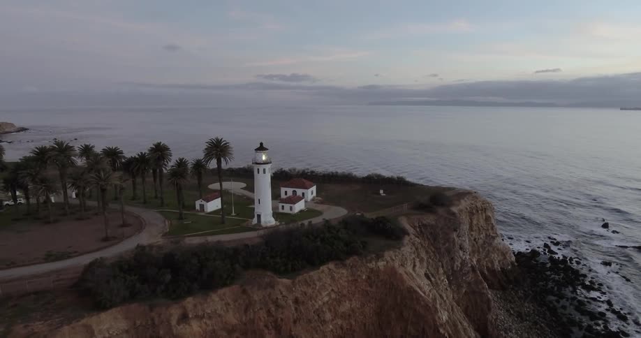 Aerial view of a lighthouse near a cliff at sunset