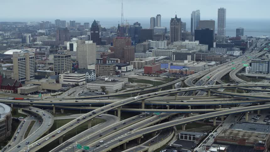 Cars traveling on a large highway system with Milwaukee skyline behind