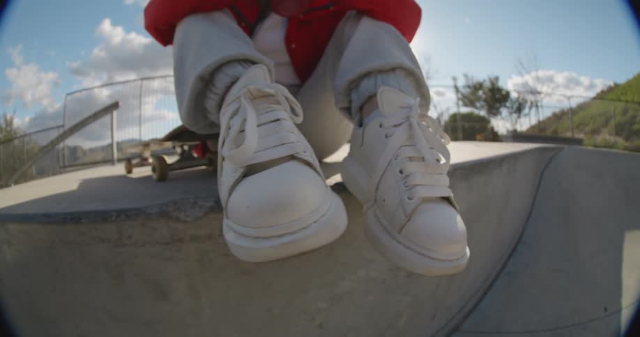 A person sits on his skateboard in the park