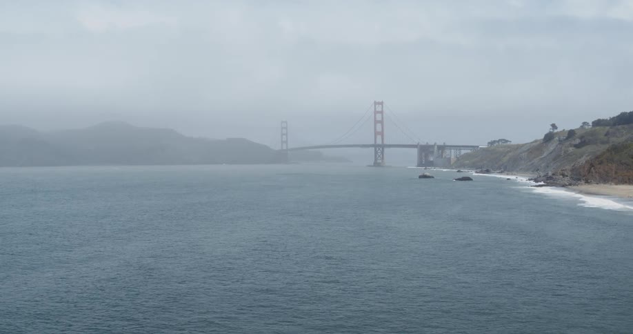 A landscape view of the ocean with a bridge in the distance