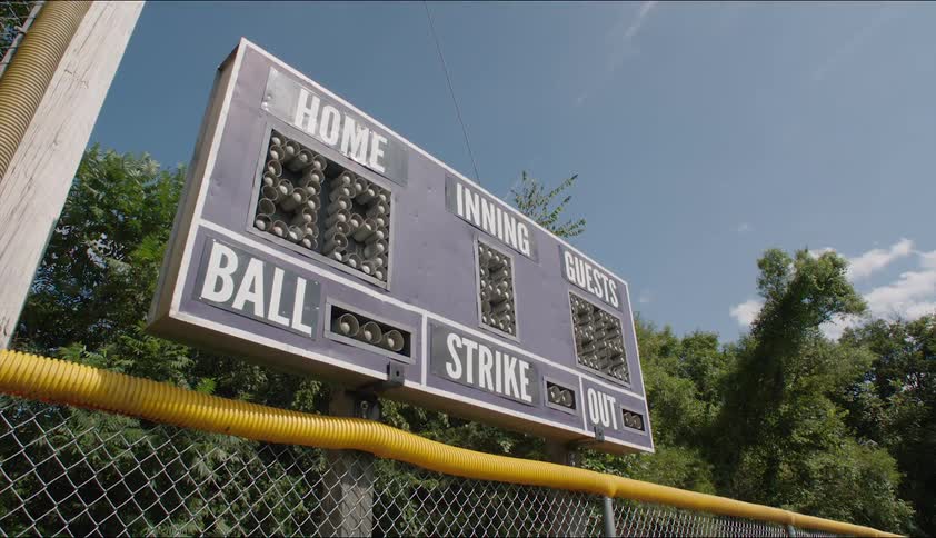 An electric scoreboard on an outdoor sports field during the day