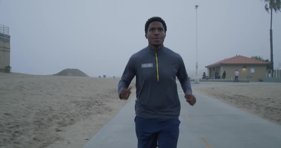 Man jogs down road moving away from people standing around house in the background
