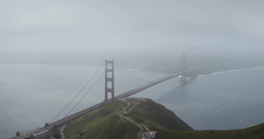 An aerial view of cars parked by a bridge over the ocean