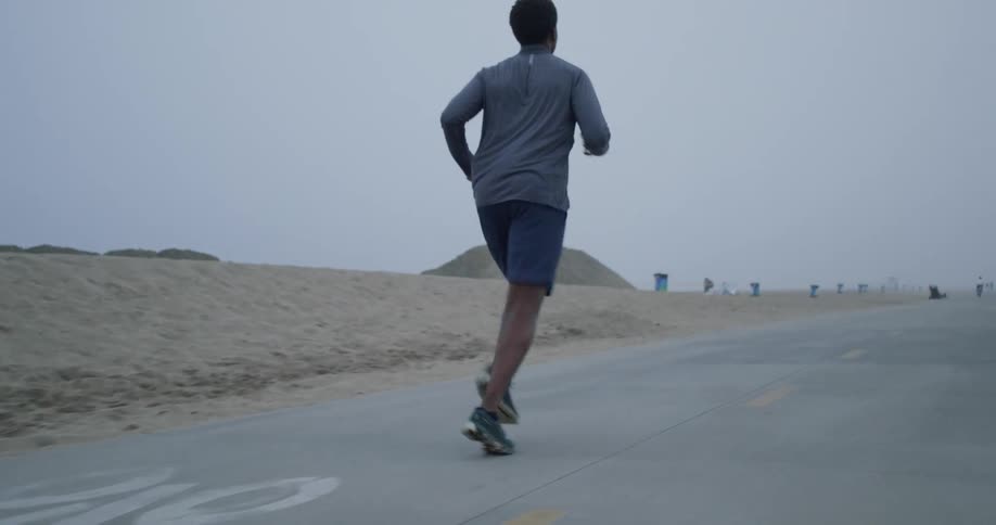 A man jogs along a bike road on a cloudy day