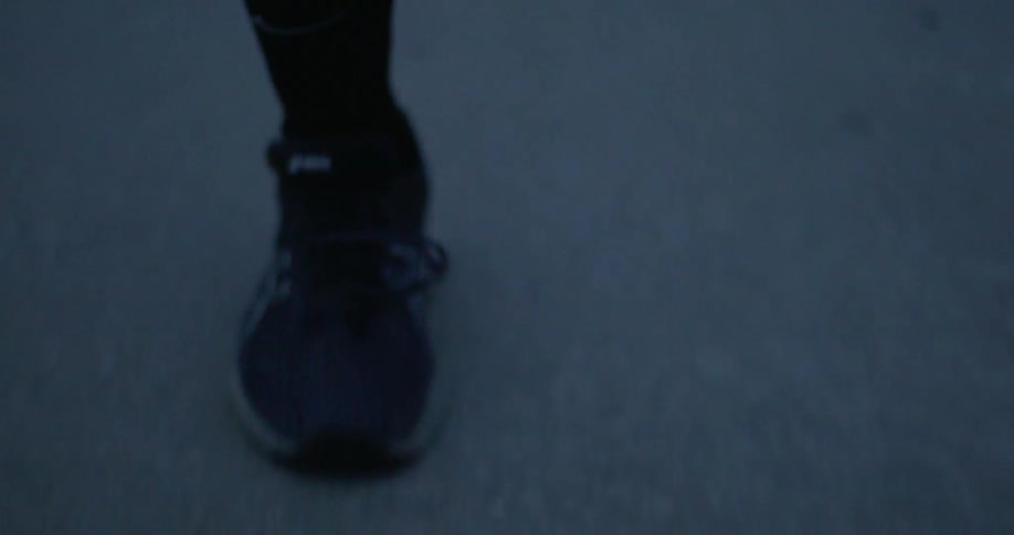 The feet of someone wearing tennis shoes running on a road
