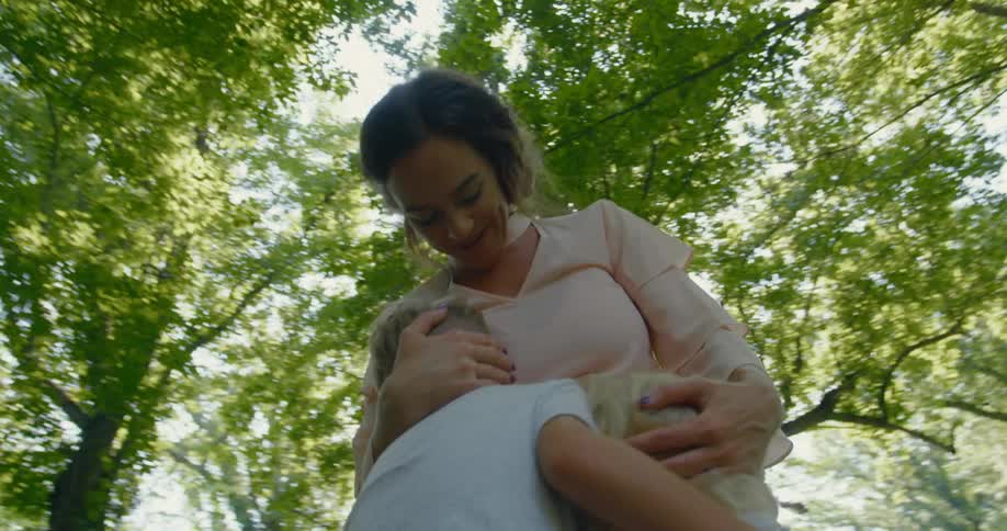 Mother and her two children hug as they stand outdoors under the trees