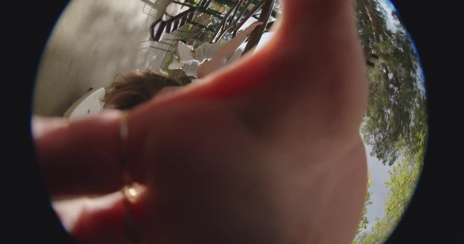 Young woman playing on a playground in a park seen through a fisheye lens