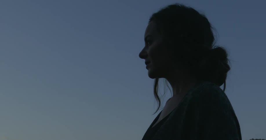 A woman stands outside and looks off in to the distance