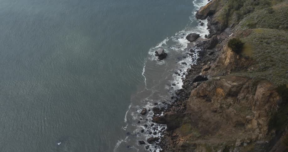Aerial view of the rocks on a beach at the base of a cliff next to the ocean