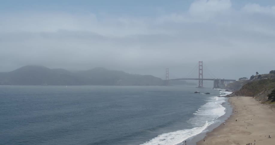 Ocean waves crash onto a trash laden beach near the golden gate bridge