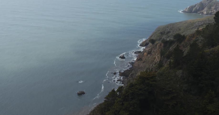 Ocean waves splash against a rocky cliff coastline
