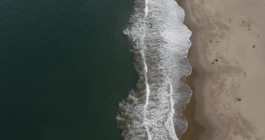 Birds eye view of waves crashing near the shoreline at the beach