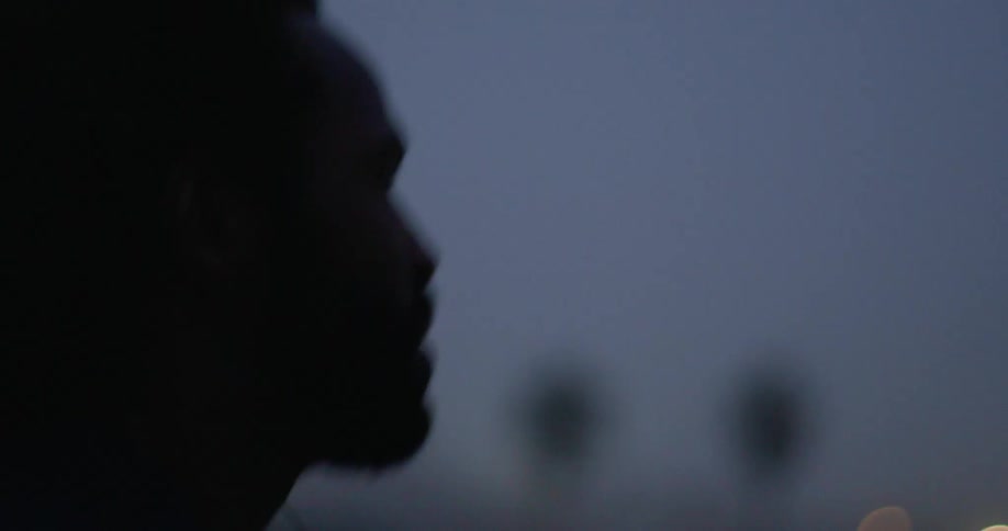 Man jobs outdoors as town lights shine in the background