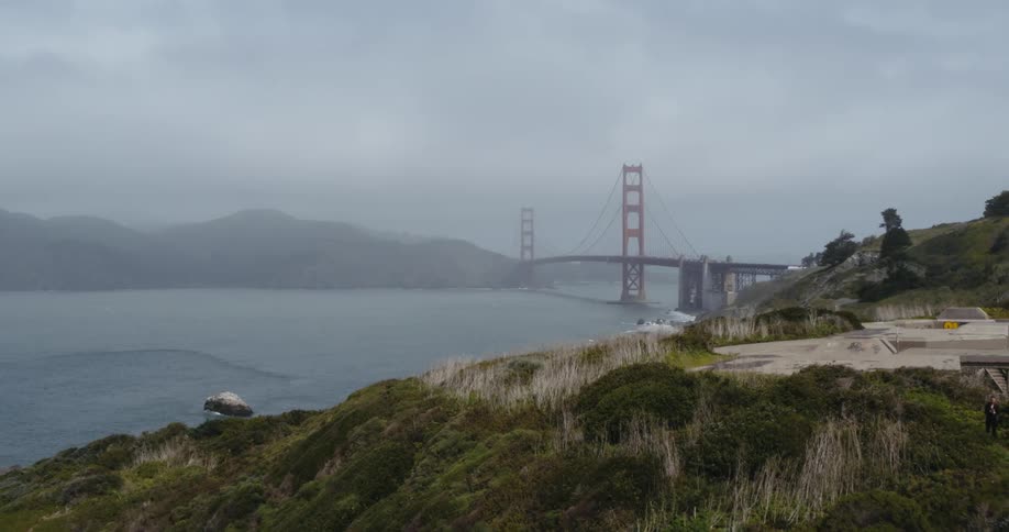 Rocky cliffs overlook the sea and the golden gate bridge