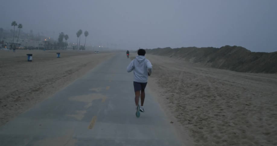 A man is running on a rural road and there is someone on a bicycle ahead of him