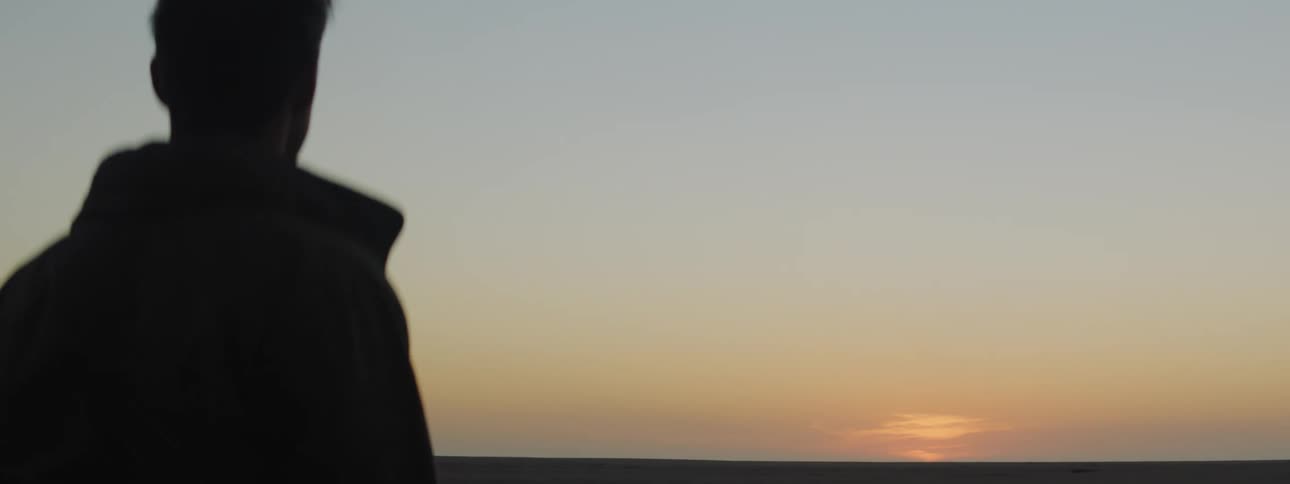 A man runs his hand through his hair as he watches the sunrise