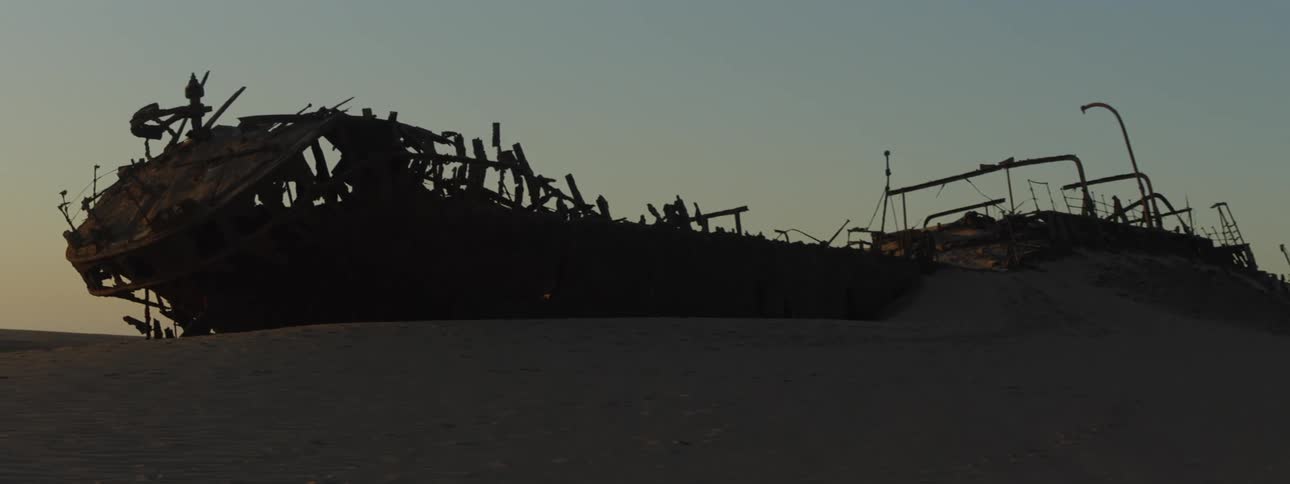 A shipwreck in the desert at dusk