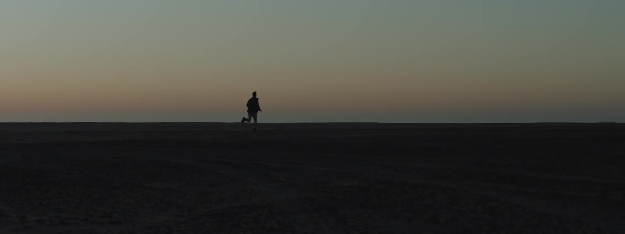 Silhouette of a man running across a desert