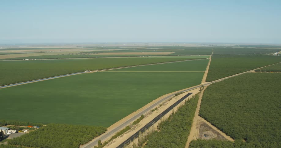 Lush green farm land with a highway and trucks cutting through