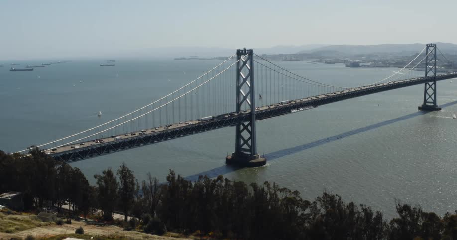 Aerial view of vehicles crossing the suspension bridge over river
